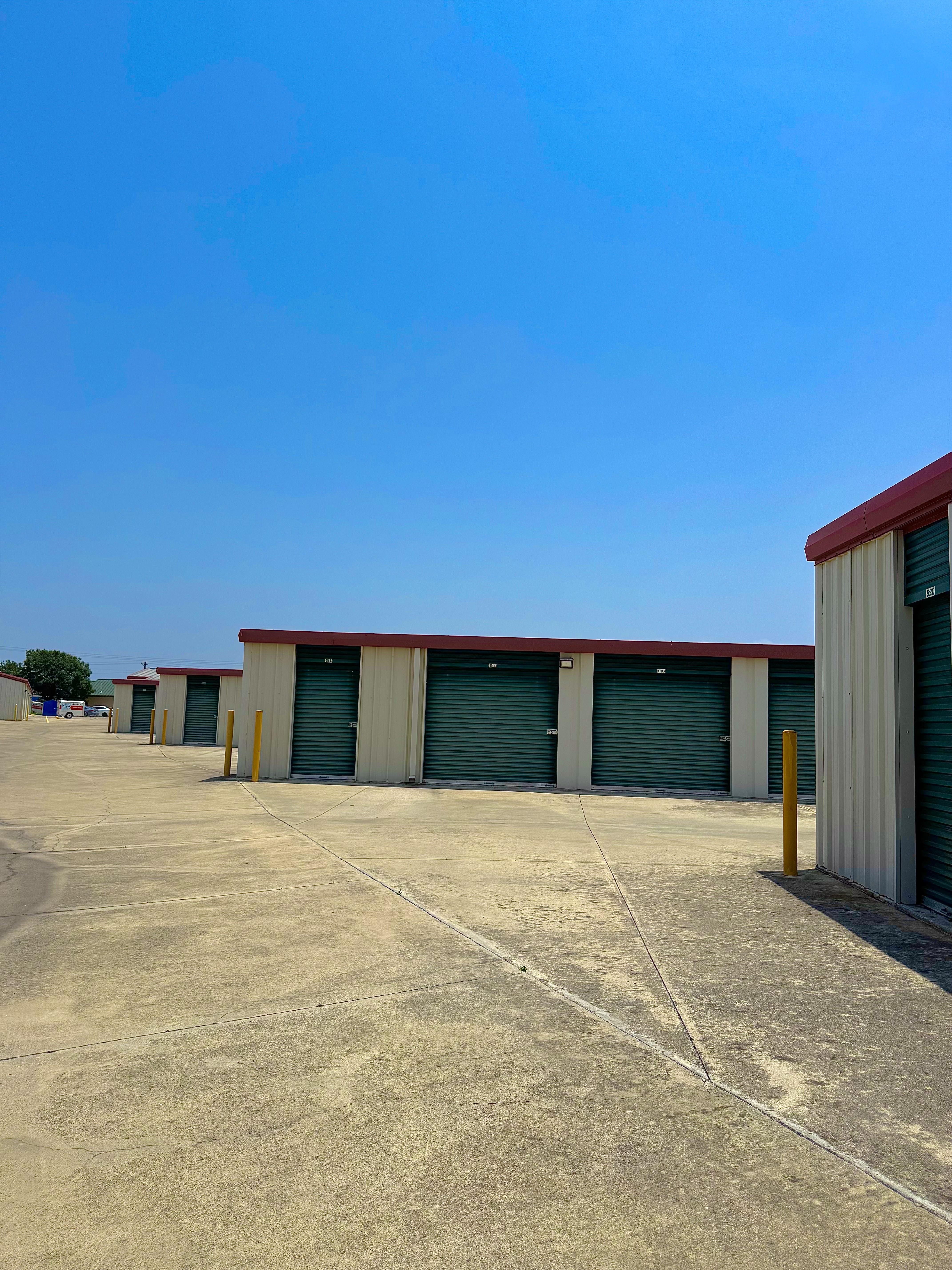 Drive-up self storage units with green roll-up doors at LockSmart Storage in Lockhart, TX, ideal for families during home renovations"